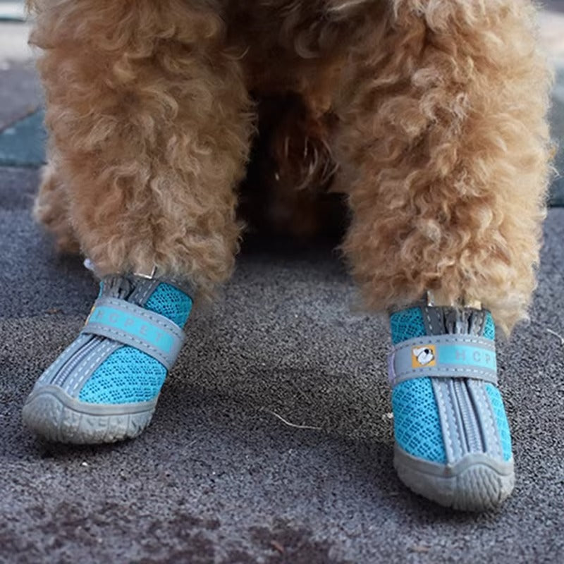 Set of four black TrekPaws protective dog boots with reflective straps resting on a modern floor.